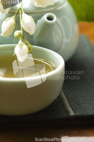 Image of Green tea with jasmine in cup and teapot on wooden table