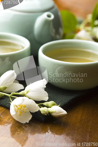Image of Green tea with jasmine in cup and teapot on wooden table