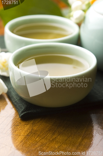 Image of Green tea with jasmine in cup and teapot on wooden table