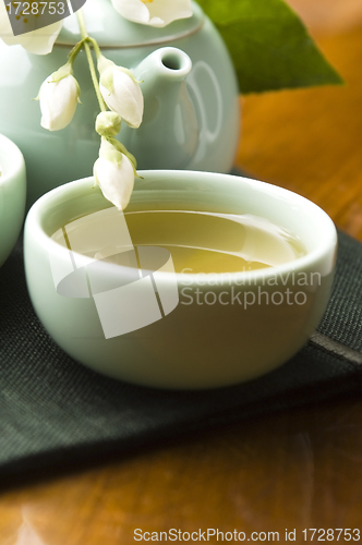 Image of Green tea with jasmine in cup and teapot on wooden table