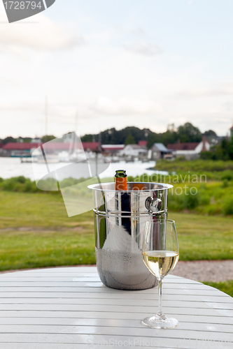 Image of Ice bucket with champagne and glass