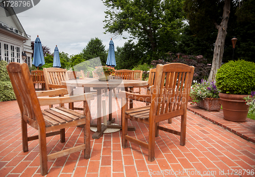 Image of Teak patio tables and chairs on brick deck