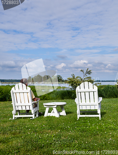 Image of Single senior man in white chairs overlooking bay