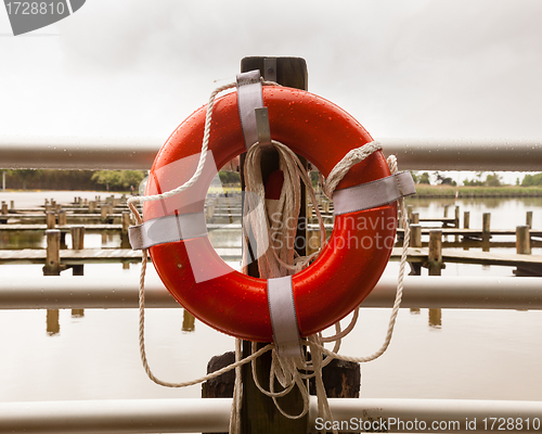 Image of Red life belt in front of empty boat dock harbor