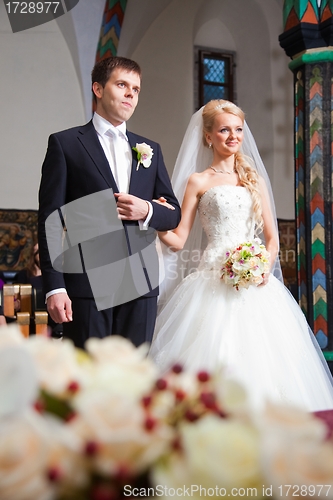 Image of groom and bride during wedding ceremony in old town hall interior