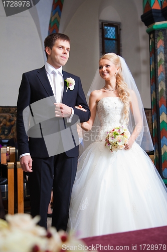 Image of groom and bride during wedding ceremony in old town hall interior