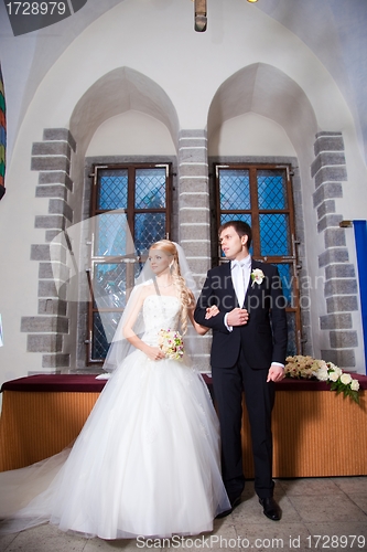 Image of groom and bride during wedding ceremony in old town hall interior