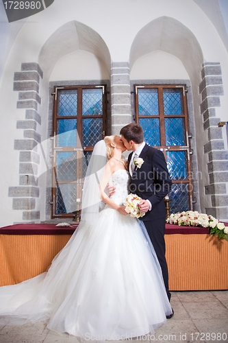 Image of first kiss of groom and bride during wedding ceremony