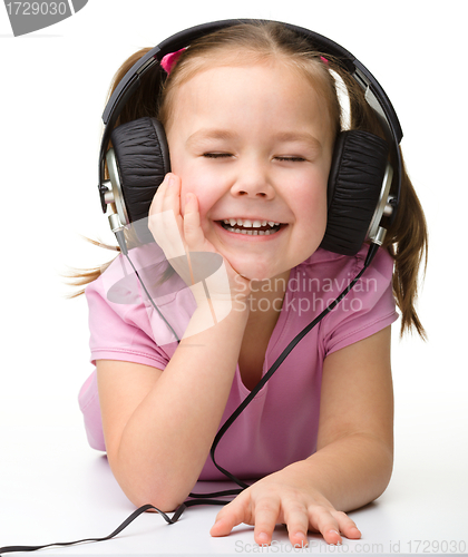 Image of Cute little girl enjoying music using headphones
