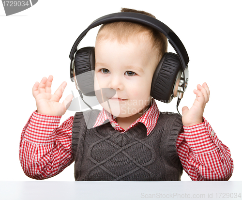 Image of Cute little boy enjoying music using headphones