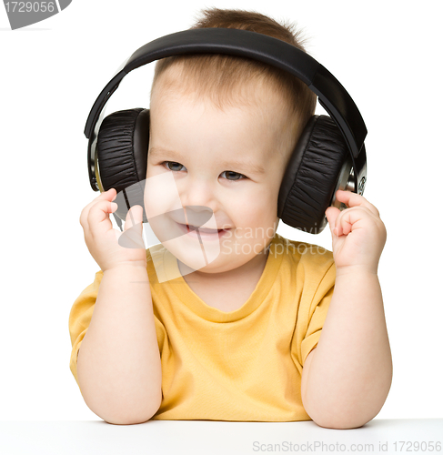 Image of Cute little boy enjoying music using headphones