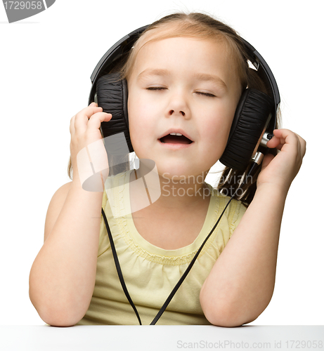 Image of Cute little girl enjoying music using headphones