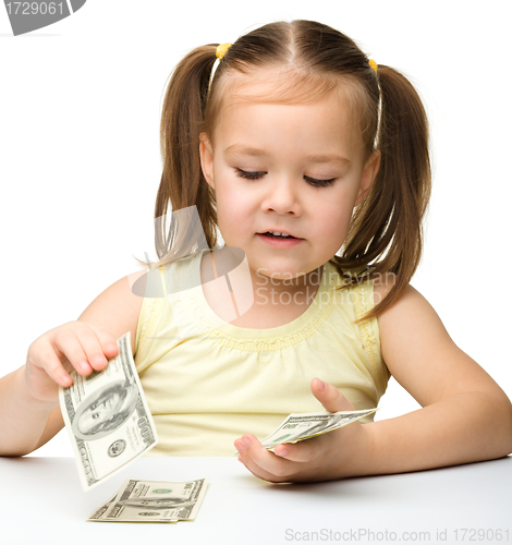 Image of Cute cheerful little girl is counting dollars