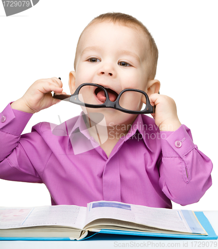 Image of Little child play with book and glasses