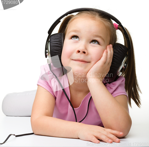 Image of Cute little girl enjoying music using headphones