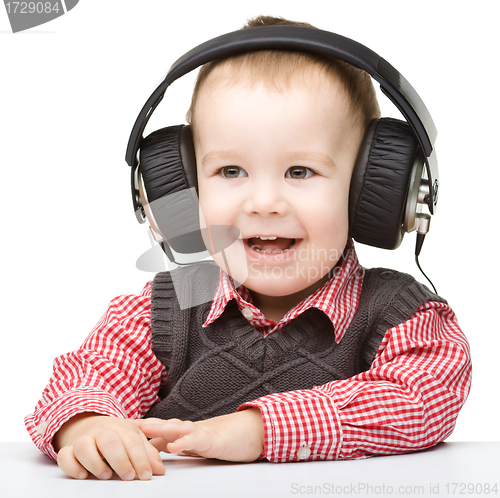 Image of Cute little boy enjoying music using headphones