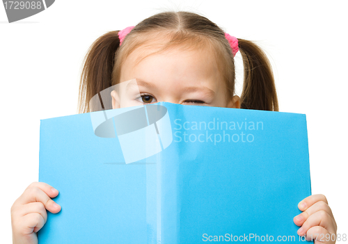 Image of Cute little girl is hiding behind a book