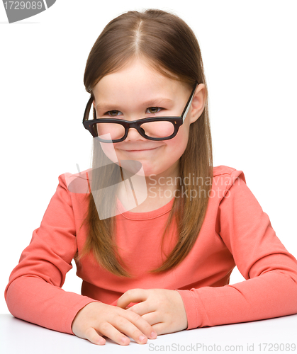 Image of Happy little girl sits at a table and smile