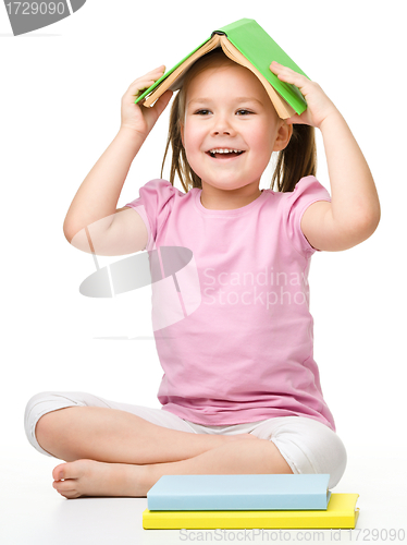 Image of Cute little girl is hiding under a book