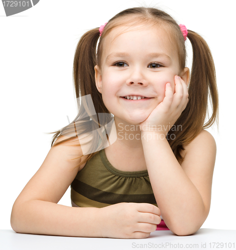 Image of Happy little girl sits at a table and smile