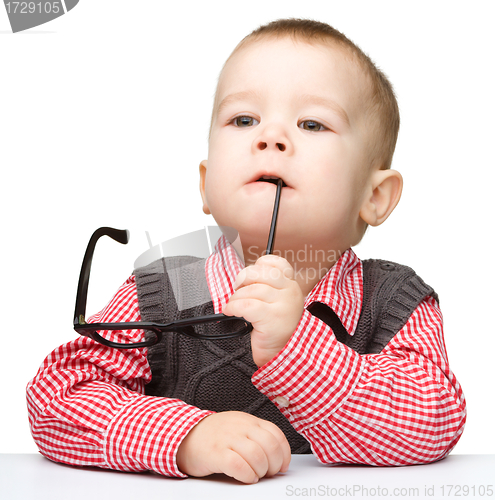 Image of Cute little child is biting glasses