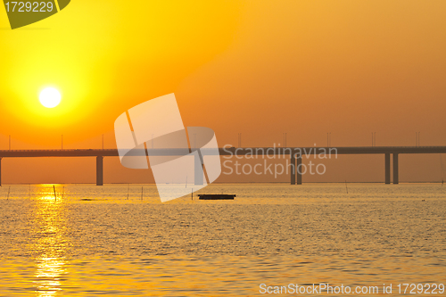 Image of Sunset over a bridge with moving boats