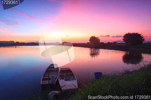 Image of Sunset along the pond with isolated boats 