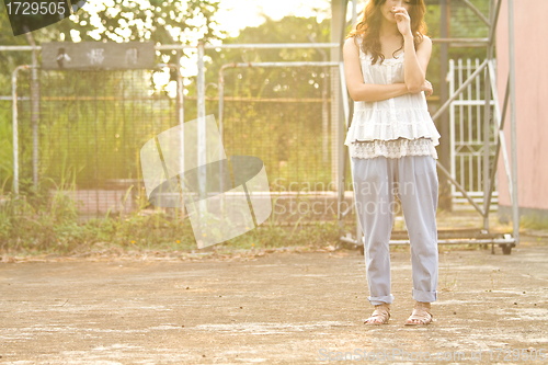 Image of Asian woman standing and thinking in basketball court, half body