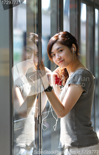 Image of Asian woman listening music in station