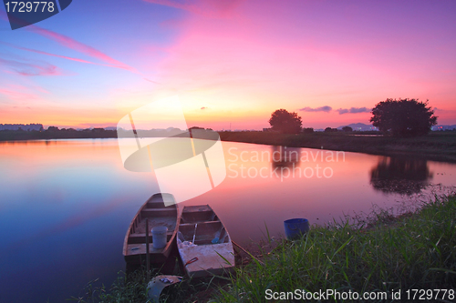 Image of Sunset along the pond with isolated boats 