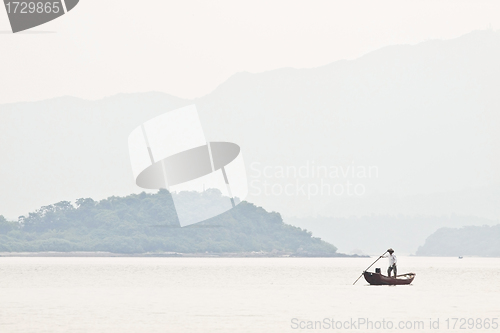 Image of A fisherman on boat alone in the sea, low saturation picture.