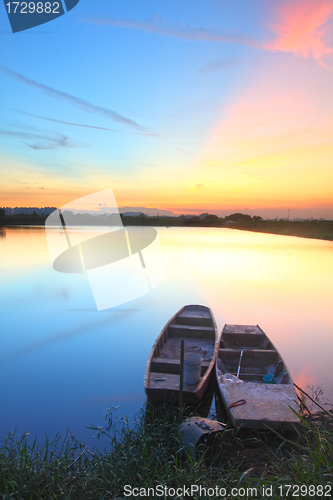 Image of Sunset with isolated boats in water body