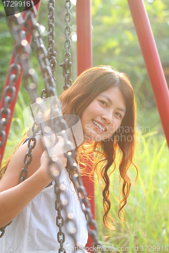 Image of A beautiful and cheerful asian girl playing swing