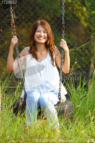 Image of Asian girl playing swing in a park