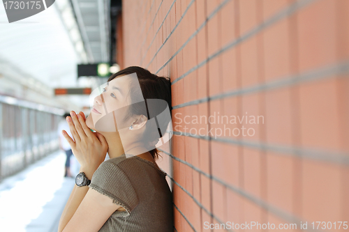 Image of Asian woman waiting for train with smile