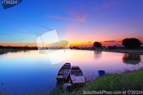 Image of Sunset along the pond with two boats and two magical color on sk