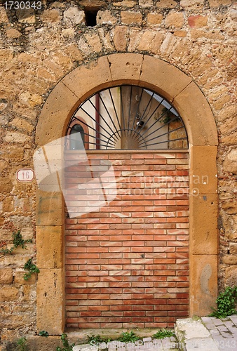 Image of Old arched door blocked by brick wall