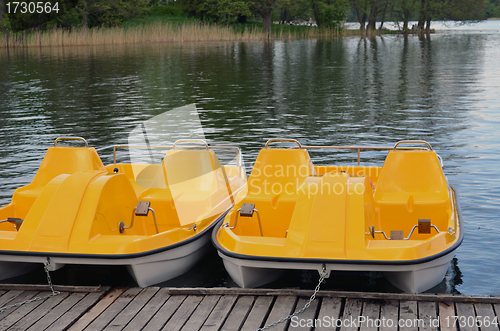 Image of Yellow water bicycles locked at lake pier 