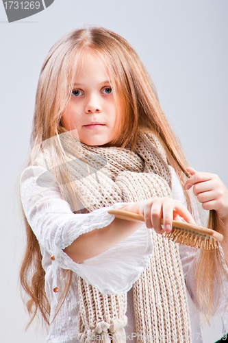 Image of Cute girl combing long blond hair