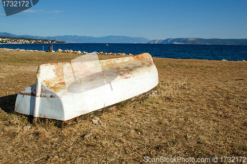 Image of old boat stranded on stone beach