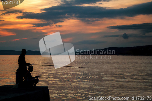 Image of Silhouettes of Fishermen on the pier at sunset 