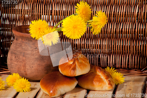 Image of three pies and dandelions in  clay pot