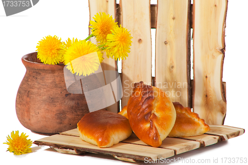 Image of three pies and dandelions in  clay pot