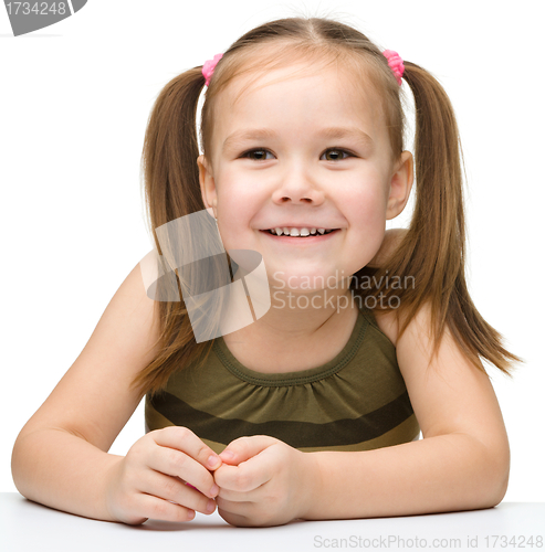 Image of Happy little girl sits at a table and smile