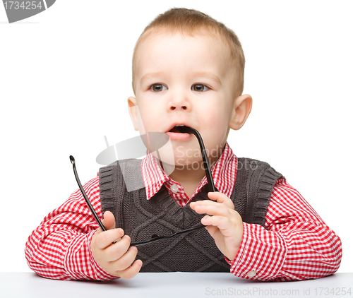 Image of Cute little child is biting glasses