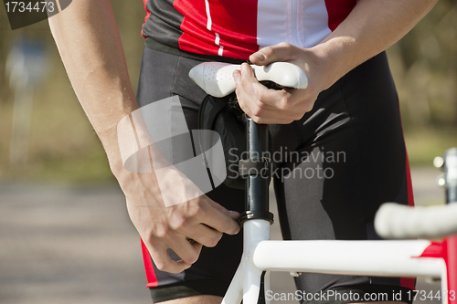 Image of Man Adjusting Seat Of Bicycle