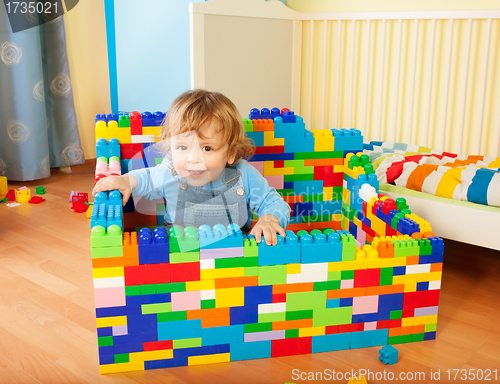 Image of toddler sitting a castle of toy blocks