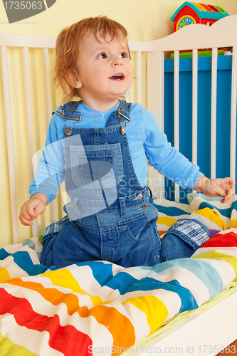 Image of Happy toddler sitting in the baby cot