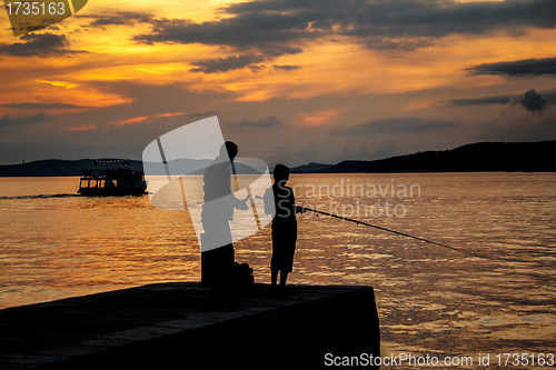 Image of Silhouettes of father and his son fishing on sea