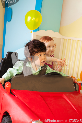 Image of Boy and girl drive toy car